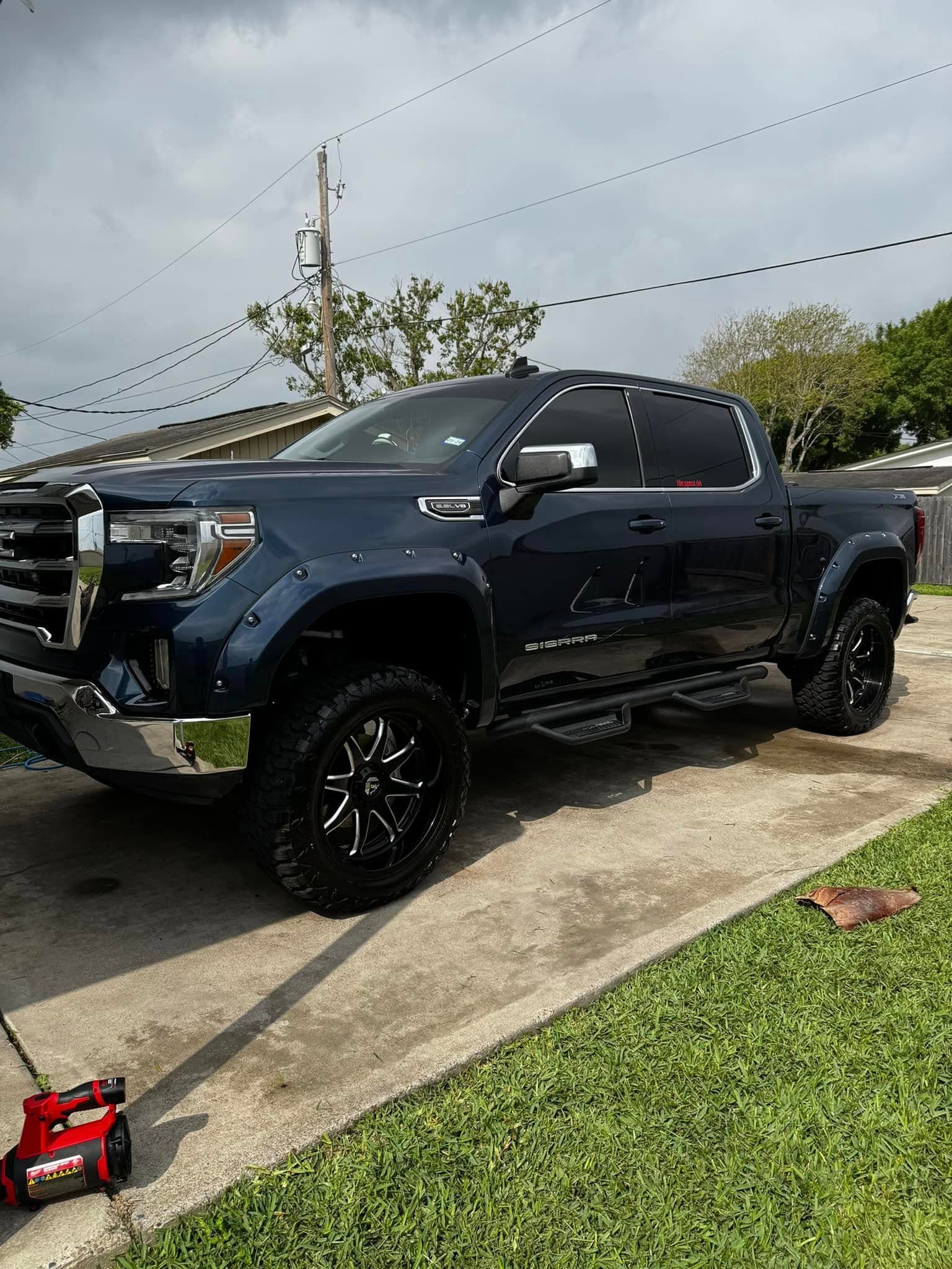 Midnight-blue lifted GMC Sierra with chrome trim polished to a shine